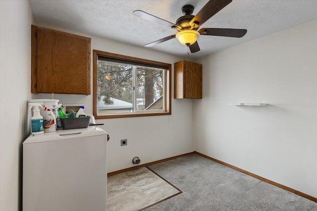 washroom with a ceiling fan, a textured ceiling, washer / dryer, cabinet space, and baseboards