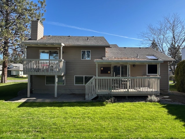 rear view of house with a lawn, a patio, a chimney, and a deck