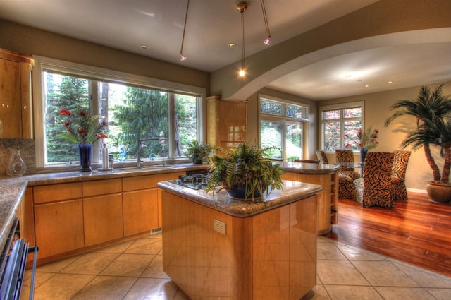 kitchen with tasteful backsplash, sink, a center island, and light tile patterned floors