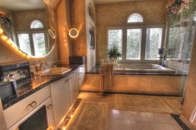 bathroom with vanity, a wealth of natural light, tile patterned floors, and a relaxing tiled tub