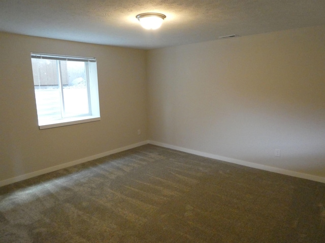 unfurnished room featuring a textured ceiling and dark colored carpet