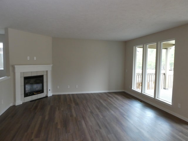 unfurnished living room with dark hardwood / wood-style flooring, a textured ceiling, and a fireplace