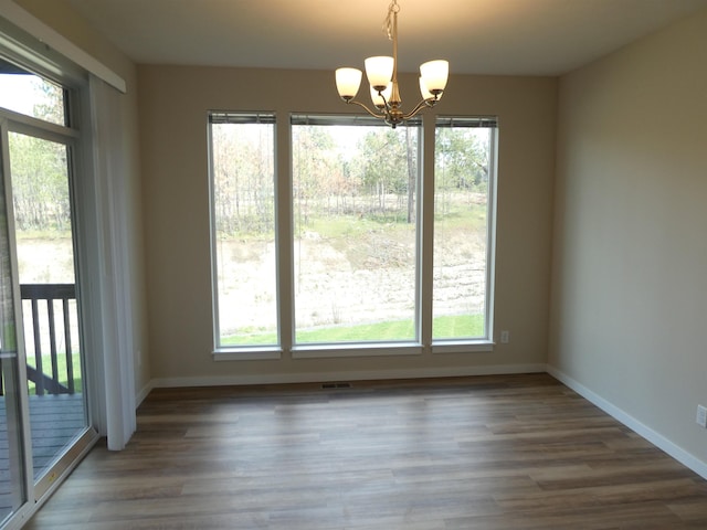 unfurnished dining area with plenty of natural light, dark hardwood / wood-style floors, and a chandelier