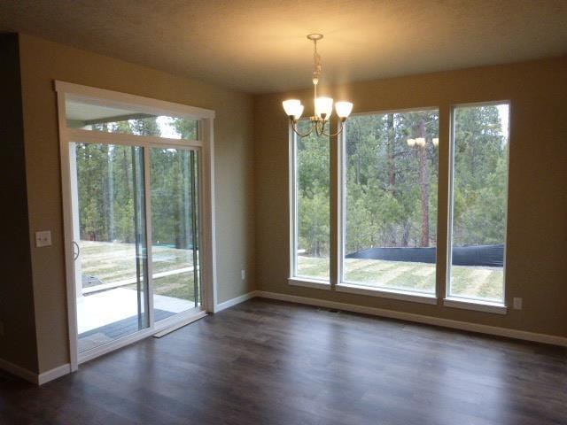 doorway to outside featuring a healthy amount of sunlight, a chandelier, and dark hardwood / wood-style flooring