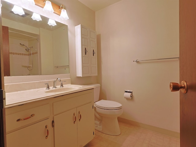 bathroom featuring a tile shower, vanity, and toilet