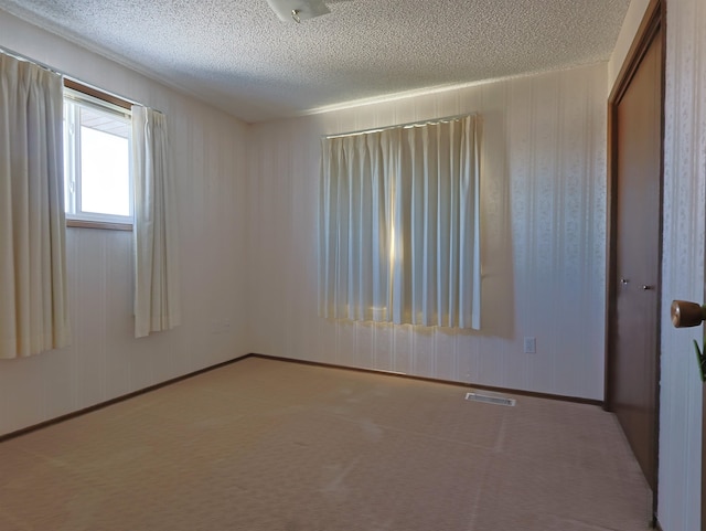 carpeted empty room featuring a textured ceiling