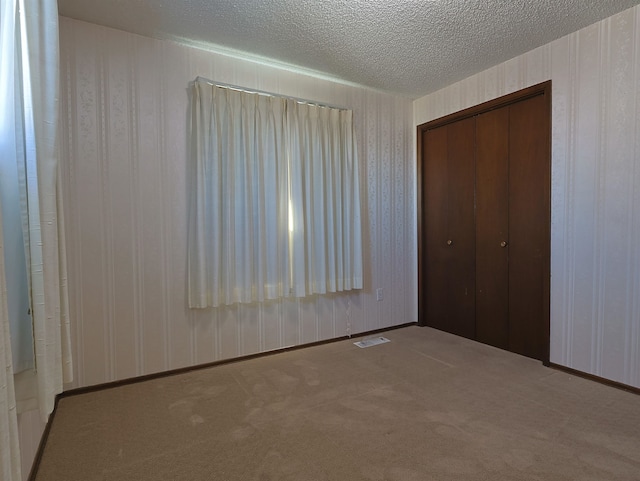 unfurnished bedroom with carpet, a textured ceiling, and a closet