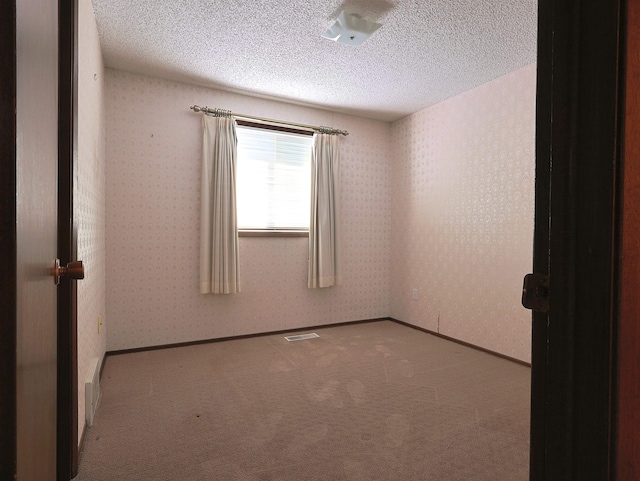 carpeted spare room with a textured ceiling