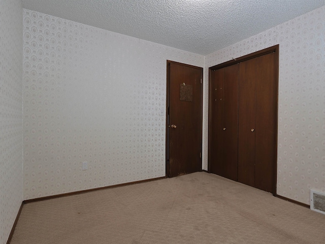 unfurnished bedroom with carpet flooring, a textured ceiling, and a closet