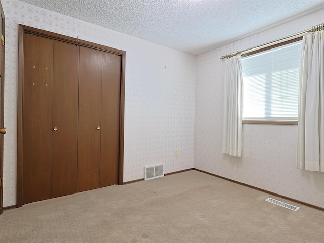 unfurnished bedroom with carpet flooring, a textured ceiling, and a closet