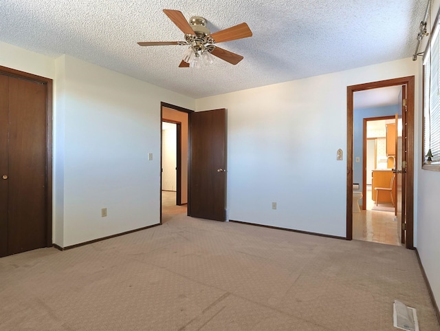 unfurnished bedroom with ceiling fan, a closet, light carpet, and a textured ceiling