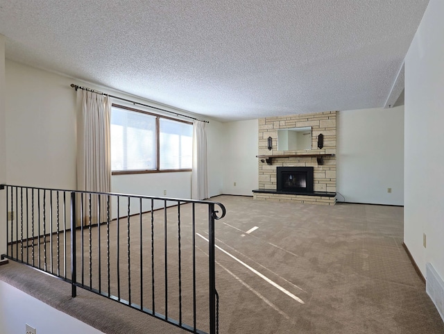 unfurnished living room with a stone fireplace, carpet floors, and a textured ceiling