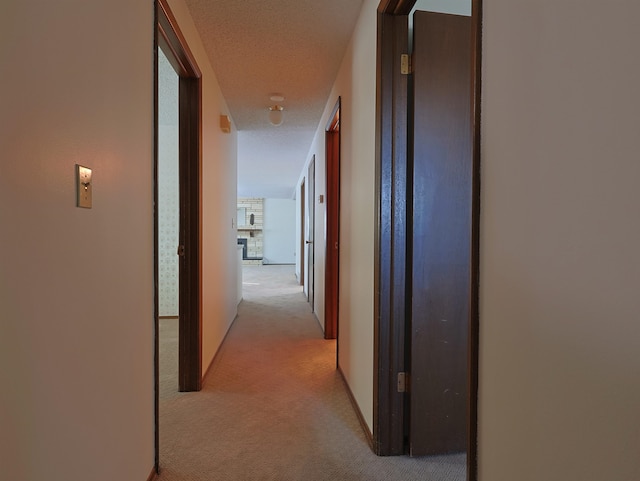 corridor featuring light carpet and a textured ceiling