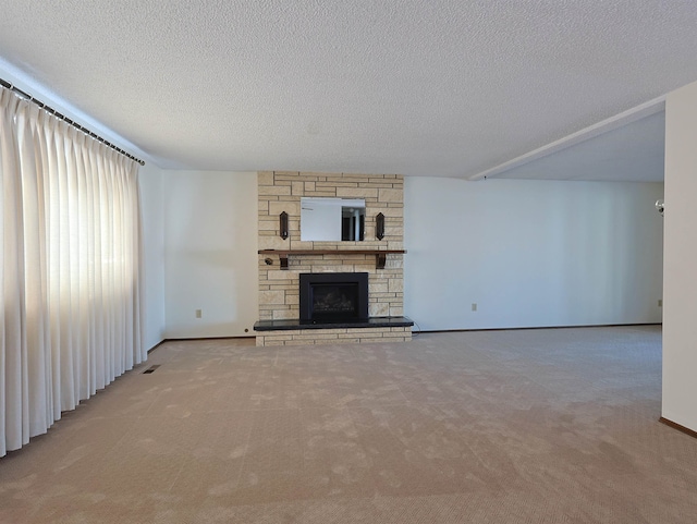 unfurnished living room featuring light colored carpet, a textured ceiling, and a fireplace