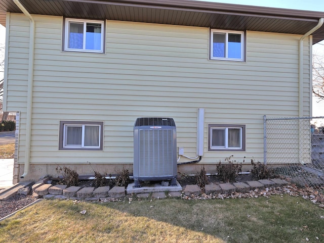 rear view of house featuring cooling unit and a lawn