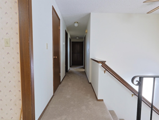 corridor featuring light colored carpet and a textured ceiling