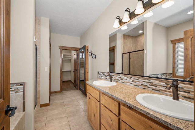 bathroom with a shower with door, vanity, tile patterned floors, and decorative backsplash