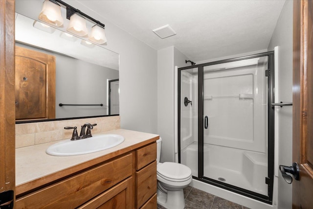 bathroom featuring vanity, a textured ceiling, a shower with shower door, and toilet