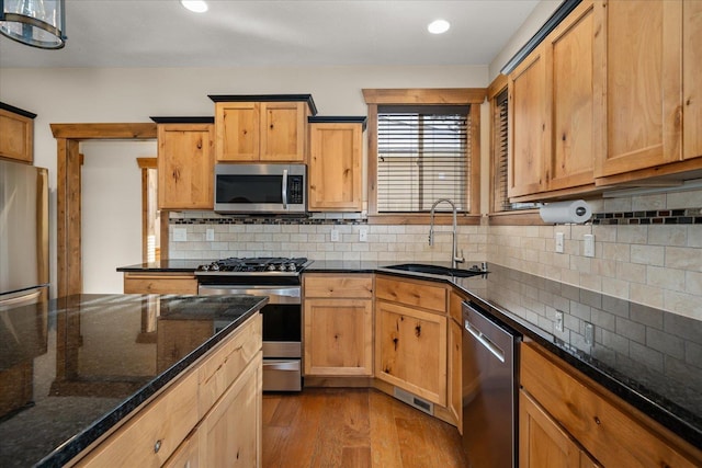 kitchen featuring tasteful backsplash, sink, dark stone countertops, light hardwood / wood-style floors, and stainless steel appliances