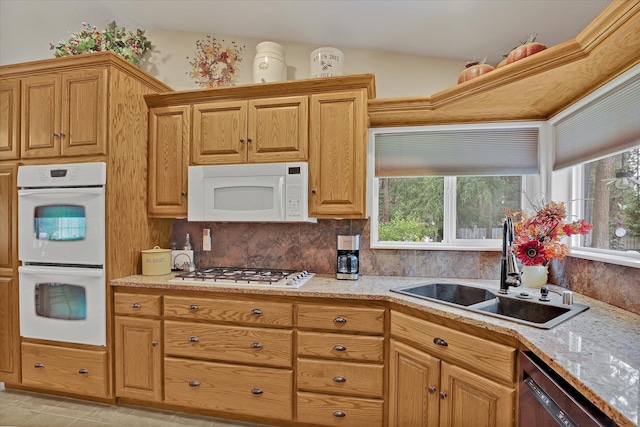 kitchen featuring vaulted ceiling, tasteful backsplash, sink, light stone counters, and white appliances