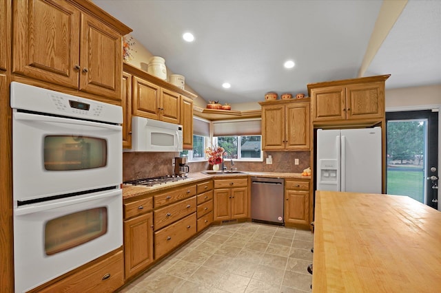 kitchen with appliances with stainless steel finishes, sink, wood counters, and decorative backsplash