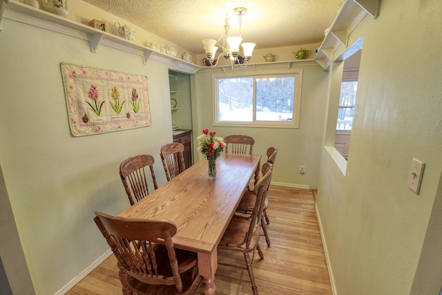 dining area featuring a notable chandelier, a textured ceiling, and light hardwood / wood-style flooring