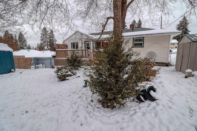 snow covered back of property featuring a deck