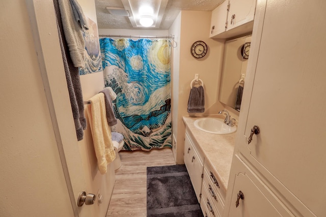 bathroom featuring hardwood / wood-style flooring, vanity, curtained shower, and a textured ceiling