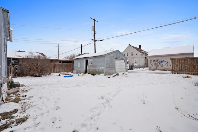 yard covered in snow featuring a garage and an outdoor structure