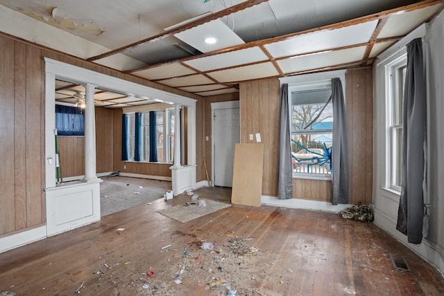 entryway featuring decorative columns, wood-type flooring, and wood walls