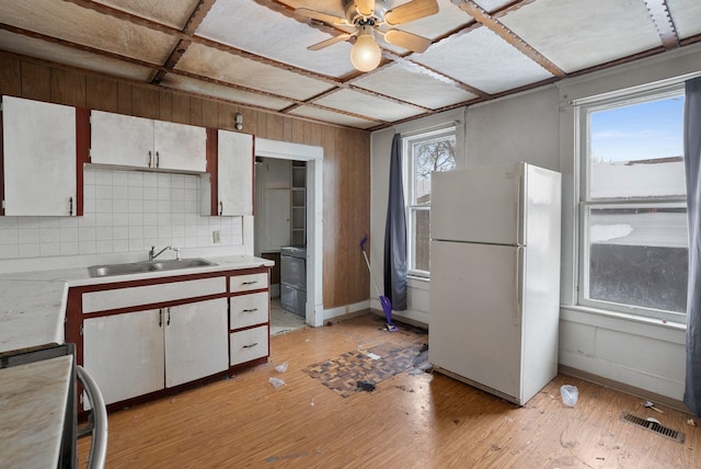 kitchen with sink, white refrigerator, light hardwood / wood-style floors, white cabinets, and decorative backsplash