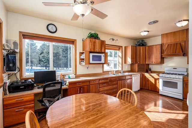 kitchen with premium range hood, sink, ceiling fan, white appliances, and light hardwood / wood-style floors