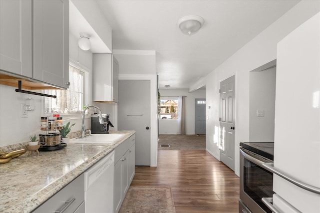 kitchen featuring sink, white dishwasher, a wealth of natural light, stainless steel electric stove, and light stone countertops