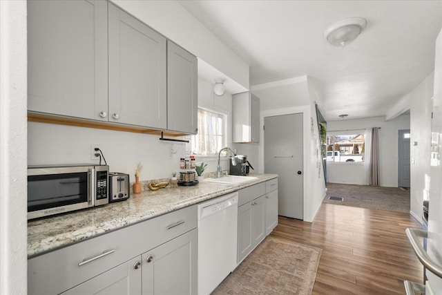 kitchen with dishwasher, light stone countertops, sink, and a wealth of natural light