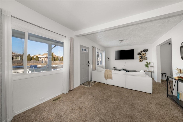 living room featuring beamed ceiling, carpet, and a textured ceiling