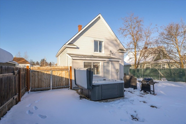 snow covered back of property featuring a hot tub