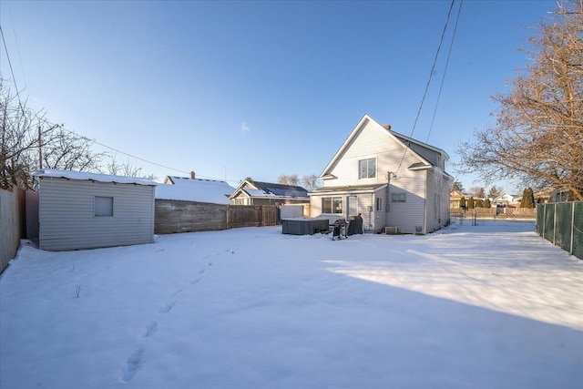 snow covered rear of property with a storage shed