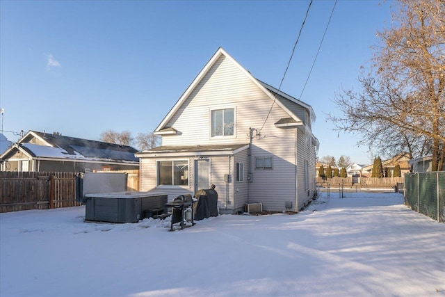 snow covered rear of property with a hot tub and central air condition unit