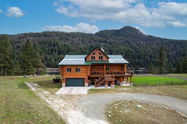 cabin featuring a rural view, a garage, a front lawn, and a deck with mountain view