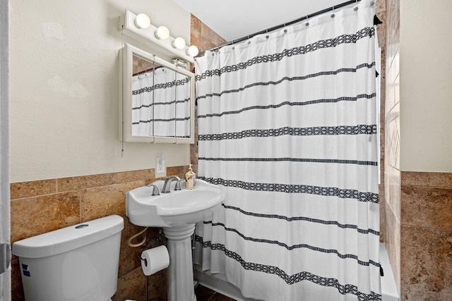 bathroom with a shower with shower curtain, tile walls, and toilet