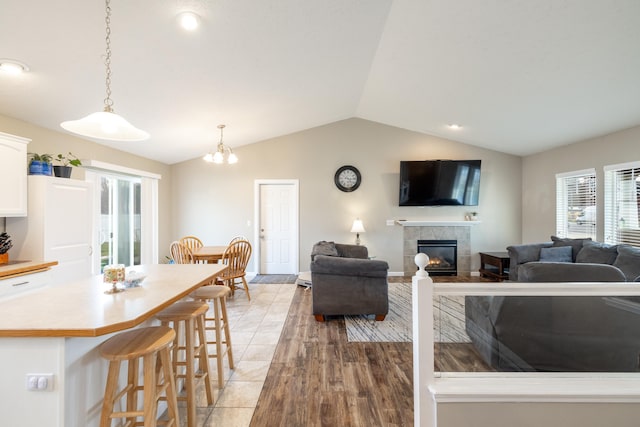 living room with a tile fireplace and lofted ceiling