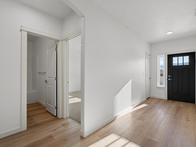 entryway featuring light wood-style flooring, arched walkways, and baseboards