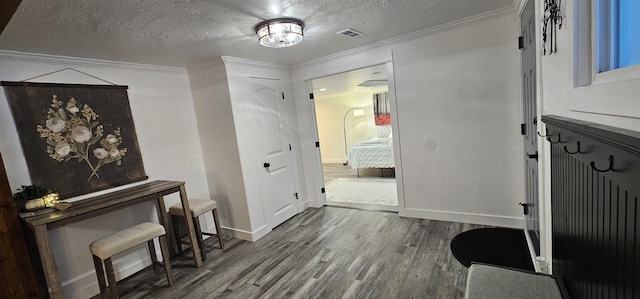 interior space featuring a textured ceiling, hardwood / wood-style flooring, and crown molding