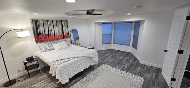 bedroom featuring a tray ceiling, dark hardwood / wood-style floors, and ceiling fan