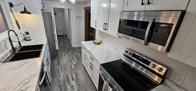 kitchen with appliances with stainless steel finishes, sink, white cabinetry, and light stone countertops