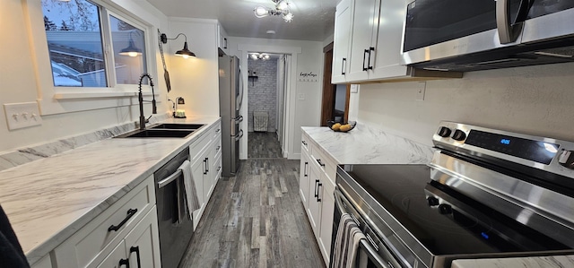 kitchen featuring white cabinetry, appliances with stainless steel finishes, sink, and light stone countertops