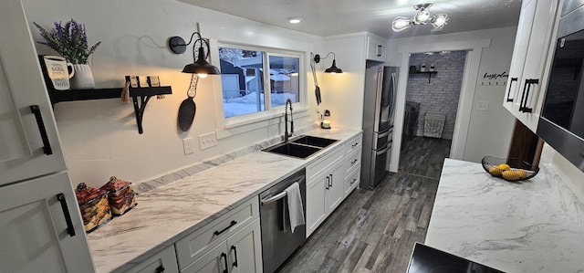 kitchen with stainless steel appliances, hanging light fixtures, sink, light stone counters, and white cabinets