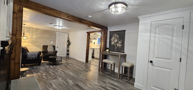 sitting room with beamed ceiling, wood walls, a textured ceiling, crown molding, and hardwood / wood-style flooring