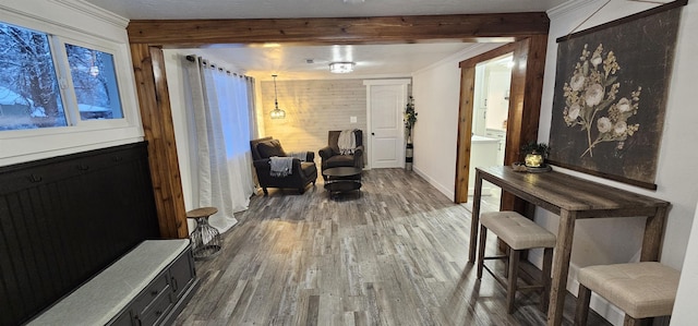 living area featuring hardwood / wood-style flooring, crown molding, beamed ceiling, and wood walls