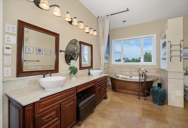 bathroom with tile walls, toilet, vanity, and a washtub